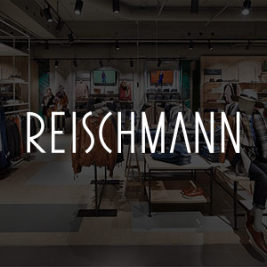 Reischmann Logo in weiß auf einem abgedunkelten Foto der Reischmann Verkaufsräume in Memmingen.