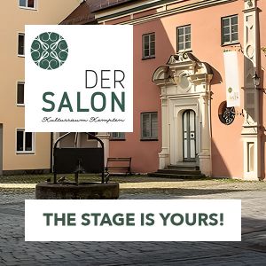 Zu sehen ist das Logo von "DER SALON" in Kempten, zudem mit der Überschrift "THE STAGE IS YOURS", jeweils auf weißen Rechtecken. Beide Elemente sind auf einem Foto des Salons.